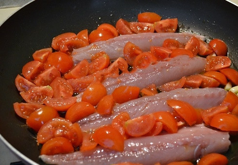 1. Этап. Скумбрия, тушенная с овощами: Разогрейте на сковороде оливковое масло, слегка обжарьте филе с дольками чеснока. Затем выложите разрезанные помидоры черри.