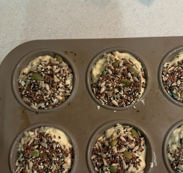 1. Этап. Закусочные сырные кексы: Тесто разложить по формам. Сверху по желанию украсить кунжутом и семечками