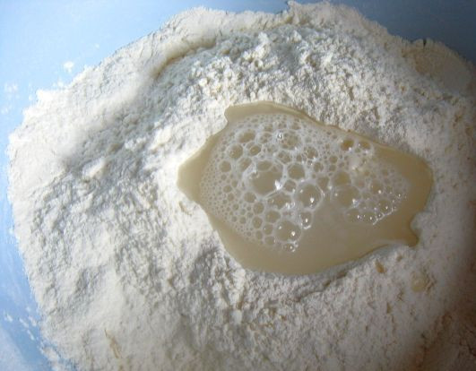 1. Этап. Бездрожжевое тесто для рыбного пирога: 2. Делаем в середине ямку и наливаем туда стакан холодной воды. Теперь постепенно при помощи лопатки или ложки начинаем замешивать тесто.