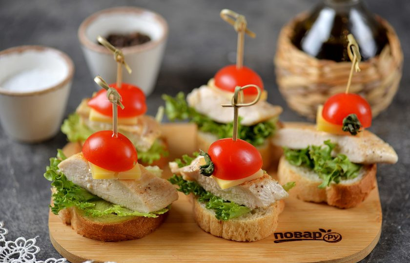 1. Этап. Канапе с курицей: Возьмите деревянную или бамбуковую шпажку, проколите ей половинку помидора черри и ломтик сыра, вставьте шпажку в курицу до хлеба.