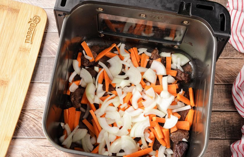 1. Этап. Плов в аэрогриле: Затем добавьте нарезанную соломкой морковь и нарезанный перьями лук. Влейте оставшееся масло и продолжайте готовить при такой же температуре около 5 минут. Пару раз мясо с овощами перемешайте.