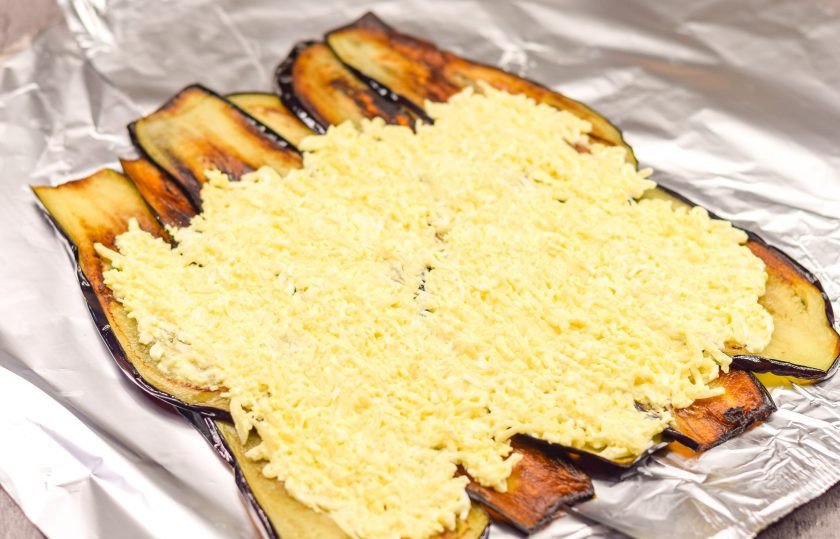 1. Этап. Рулет из баклажан, яиц и ветчины: Поверх баклажанов выложите приготовленную начинку из сыра и яиц.