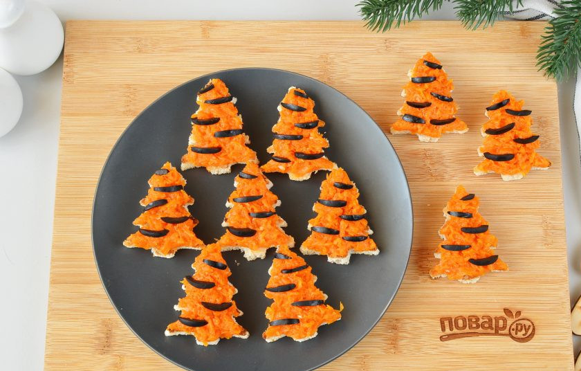 1. Этап. Брускетты Елочки на Новый год Тигра: Соберите брускетты. На каждую елочку выложите щедро тыкву с печеным чесноком, украсьте тонкими полосочками маслин, имитируя тигровый окрас.