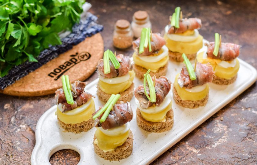 1. Этап. Канапе с килькой и яйцом: Добавьте зеленый лук на канапе.