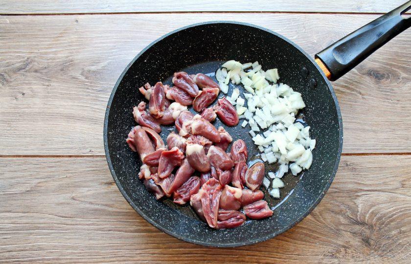 1. Этап. Булгур с куриными сердечками: В сковороду налейте растительное масло, выложите мелко резаный репчатый лук. Куриные сердечки очистите от лишнего жира и пленок, разрежьте пополам и добавьте в сковороду к луку.
