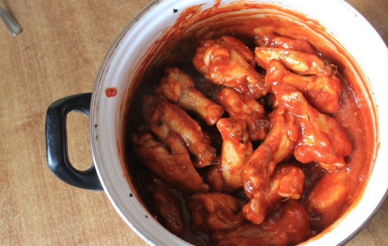 1. Этап. Куриные крылышки Баффало: Вливаем соус и перемешиваем, встряхнув кастрюлю.