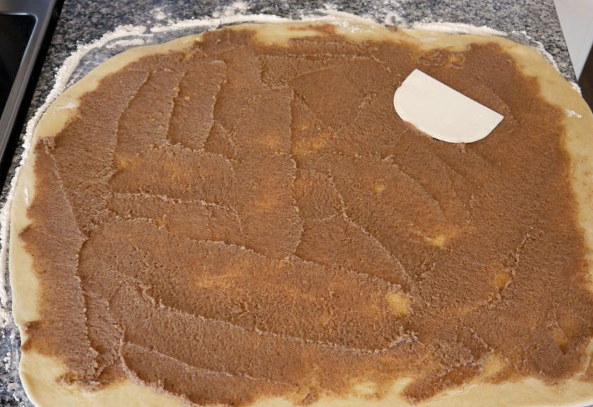 1. Этап. Плюшки Улитки: 4. Смешайте оставшееся сливочное масло, коричневый сахар, молотую корицу. Выложите смесь на пласт теста и максимально равномерно распределите по нему.