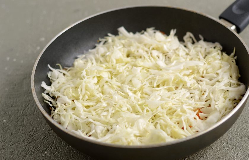 1. Этап. Макароны с капустой: Капусту тонко нашинкуйте, сожмите руками. Добавьте капусту в сковороду, посолите и тушите под крышкой 15-20 минут.