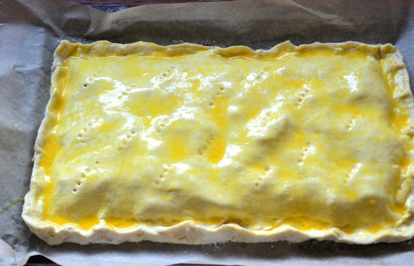 1. Этап. Пирог с начинкой из сыра и ветчины: Накройте сверху второй частью теста, вилкой сделайте несколько проколов, чтобы избежать вздутия при запекании. Смажьте верх пирога взбитым яйцом, отправьте в духовку на 25 минут (температура запекания — 180 градусов).