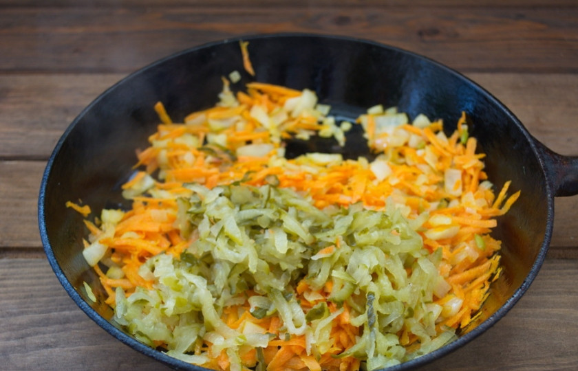 1. Этап. Солянка с сосисками: Соленый огурец натираем на терку. Добавляем к овощам. Тушим.