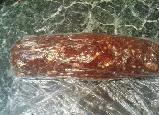 1. Этап. Пирожное Колбаска из печенья: Теперь возьмите целлофановую плёнку или обычкновенный целлофановый пакет. Из получившейся массы нужно сформировать плотную колбаску желаемой толщины. Эту колбаску заверните в плёнку и отправьте в морозильник на 30 минут.