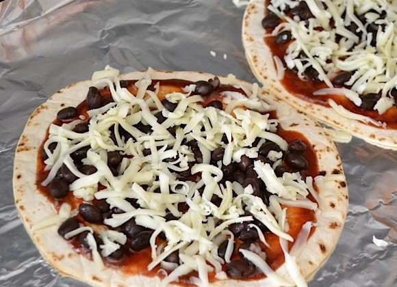 1. Этап. Мини-пицца из тортильи: 4. Натрите на терке твердый сыр и посыпьте им фасоль.