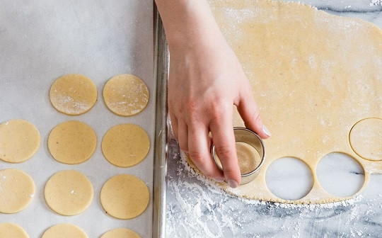 1. Этап. Рождественское печенье со сгущенкой: 5. Разогрейте духовку до 180 градусов. Раскатайте тесто довольно тонко. Вырежьте около 50 небольших кружочков, которые выложите на противень, застеленный пергаментом.