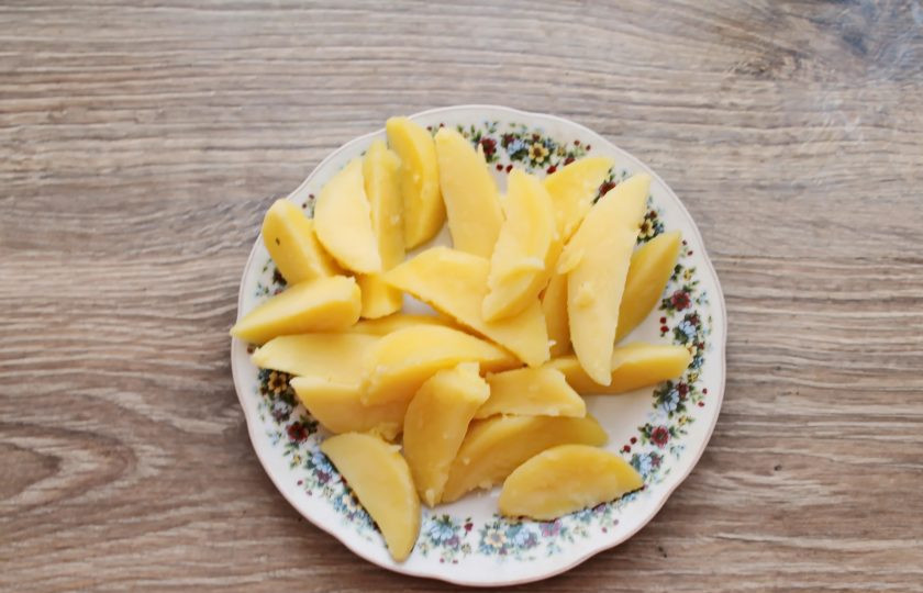 1. Этап. Радужная форель в духовке с овощами: Картофель почистите и порежьте дольками. Отварите в соленой воде в течение 10 минут на среднем огне после закипания. Картофель должен свариться наполовину, слейте воду.