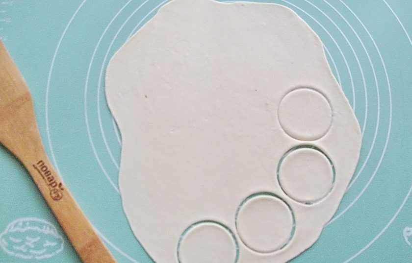 1. Этап. Пельмени из свинины и курицы: Отрежьте кусочек теста, раскатайте в тонкий пласт. С помощью любой выемки сделайте кружки на тесте.