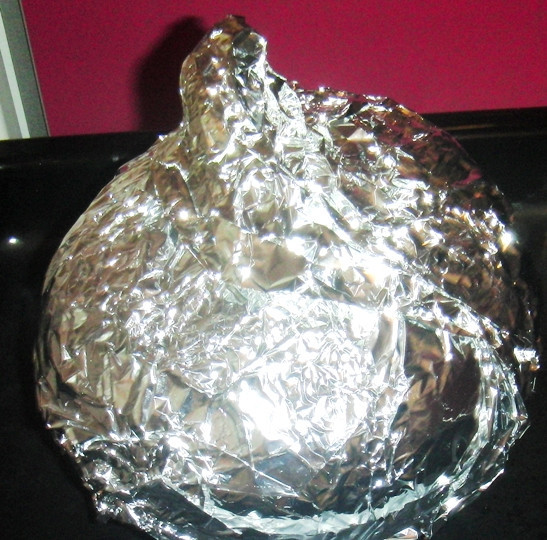 1. Этап. Куриное рагу в тыкве: Тесно обверните тыкву фольгой. Хвостик на крышечке тоже закройте, иначе она обгорит. Поместите завернутую в фольгу тыкву в нагретую духовку и запекайте при температуре 180-200 градусов около 2 - 3 часов.