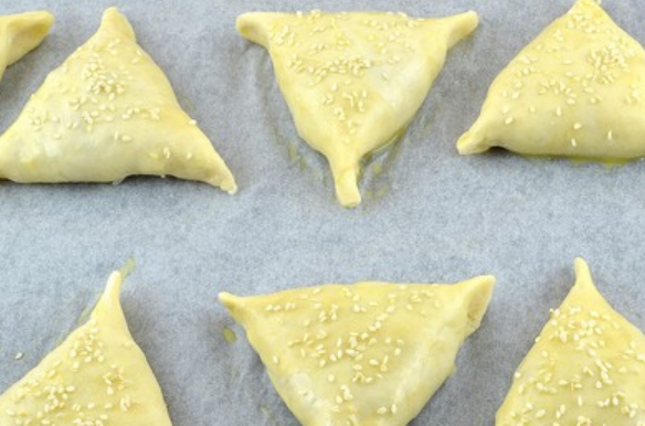 1. Этап. Самса с куриным филе: Застилаем противень бумагой для выпечки, выкладываем на него самсу. Смазываем пирожки взбитым яйцом, посыпаем кунжутом. Выпекаем в духовке 40 минут, температура 180 градусов.