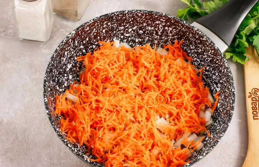 1. Этап. Подлива из лука, моркови, сладкого перца и томата: Морковь натрите на терке с мелкими ячейками и выложите ее на сковороду. Перемешайте и обжарьте примерно 2 минуты.