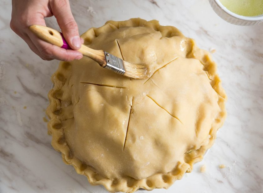 1. Этап. Пирог с ароматными яблоками: Накрываем яблоки вторым слоем теста, отрезаем лишнее, делаем надрезы сверху и смазываем поверхность пирога взбитыми яйцами.