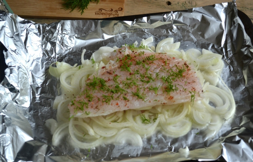 1. Этап. Пангасиус в духовке под сыром: Филе пангасиуса посолите и натрите специями для рыбы, положите его на луковую подушку, присыпьте мелко рубленным укропом.