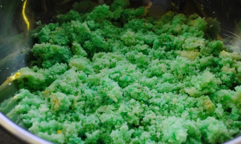 1. Этап. Кейкпопсы Рождественский сюрприз: Бисквит измельчите в крошку. А потом добавьте к ней зелёный краситель. Тщательно всё перетрите.