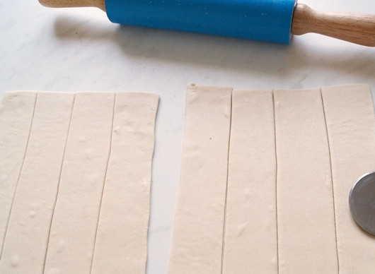 1. Этап. Слойки с курицей: Наше тесто успело разморозиться. Слегка раскатываем листы теста и нарезаем на полоски.