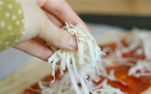 1. Этап. Закрытая пицца Стромболи: 2. Присыпьте тесто половиной тертого сыра.