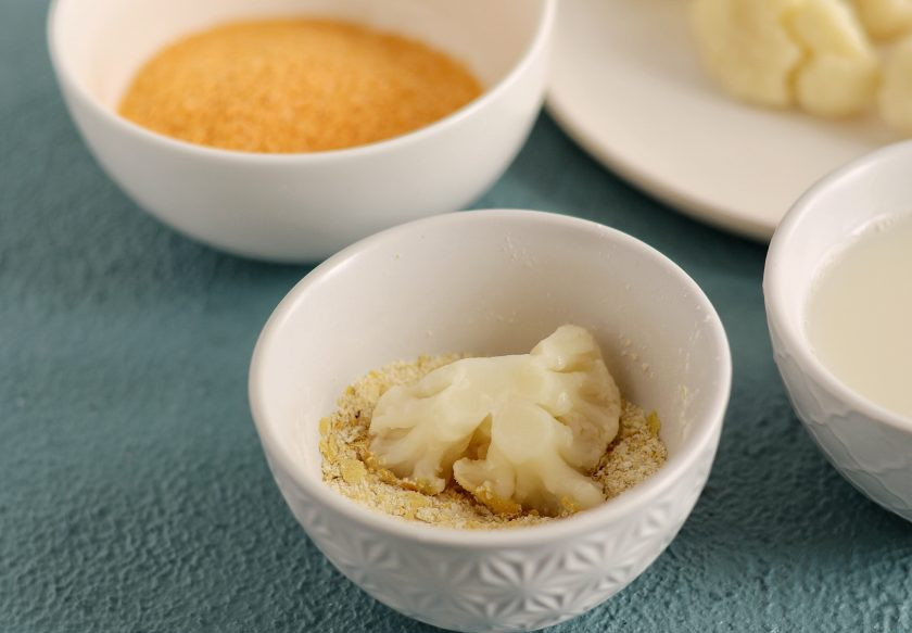 1. Этап. Наггетсы из капусты: Смешайте в отдельной миске муку, крахмал, специи и соль. Окуните цветную капусту в соевое молоко, затем обваляйте в мучной смеси.