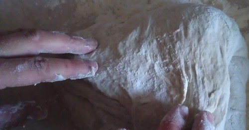 1. Этап. Домашний хлеб на закваске: На рабочую поверхность насыпьте просеянную пшеничную муку высшего сорта. Выложите на муку тесто для хлеба. Обминайте его руками, сворачивая бока теста во внутрь, чтобы оно 