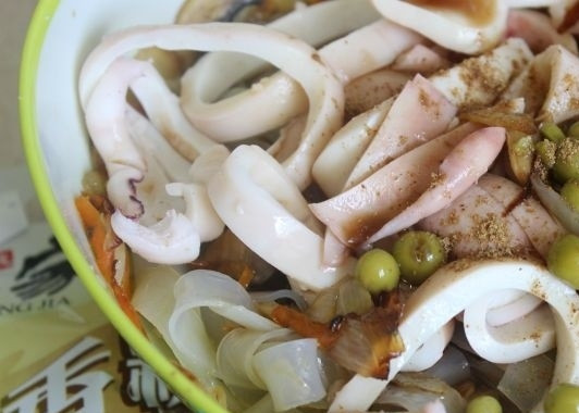 1. Этап. Салат с кальмарами и шампиньонами: 5. Кальмары остудите немного и нарежьте кольцами. Добавьте в салатник вместе с зеленым горошком. Приправьте щепоткой соли и специями по вкусу.