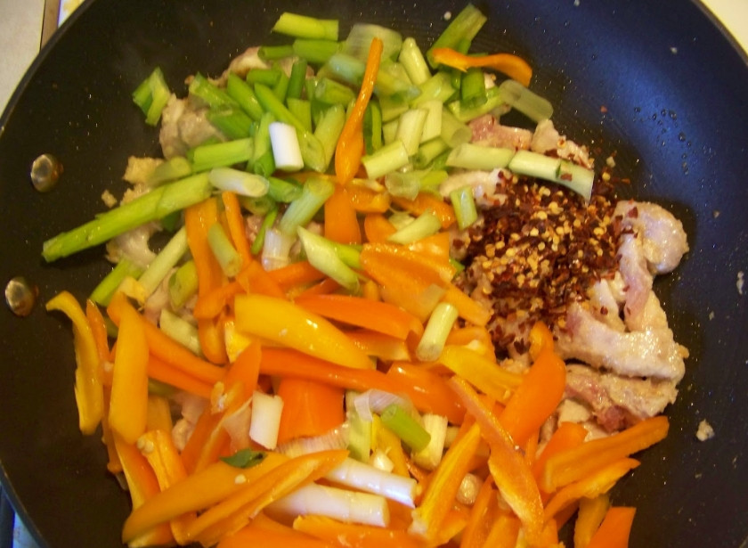 1. Этап. Свинина жареная с болгарским перцем: 5. К слегка обжаренному мясу отправить овощи. При желании можно также добавить немного хлопьев красного перца.