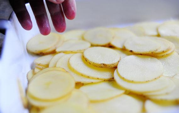 1. Этап. Запеченный картофель с ветчиной: 5. Нарезать картофель ломтиками толщиной 3 мм. Выложить 1/3 картофеля в смазанное маслом блюдо.