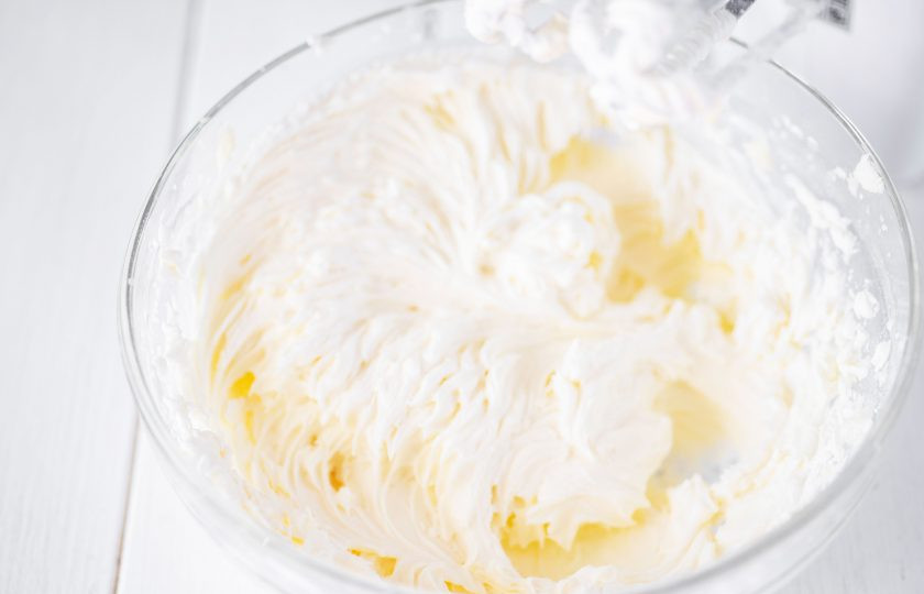 1. Этап. Торт с вишней и ананасом: В просторной миске взбейте миксером жирные сливки до кремообразного состояния, затем добавьте к ним сливочный сыр, сахарную пудру и ванилин — взбивайте все миксером до получения гладкого, однородного, воздушного крема.