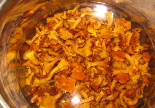 1. Этап. Яичница с лисичками: Выкладываем грибы в кастрюлю, заливаем водой и ставим на огонь, доводим жидкость до кипения, после чего сливаем ее, а грибы промываем. Опять заливаем лисички водой, добавляем соль по вкусу и варим грибы в течение 25-30 минут, затем откидываем их на дуршлаг и промываем.