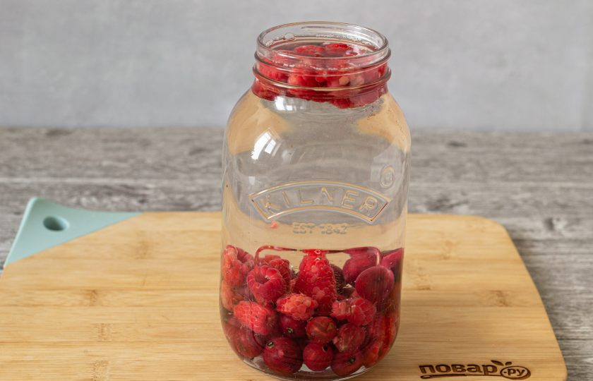 1. Этап. Компот из крыжовника с малиной: Влейте горячую воду, прикройте банку крышкой и оставьте на 10 минут.