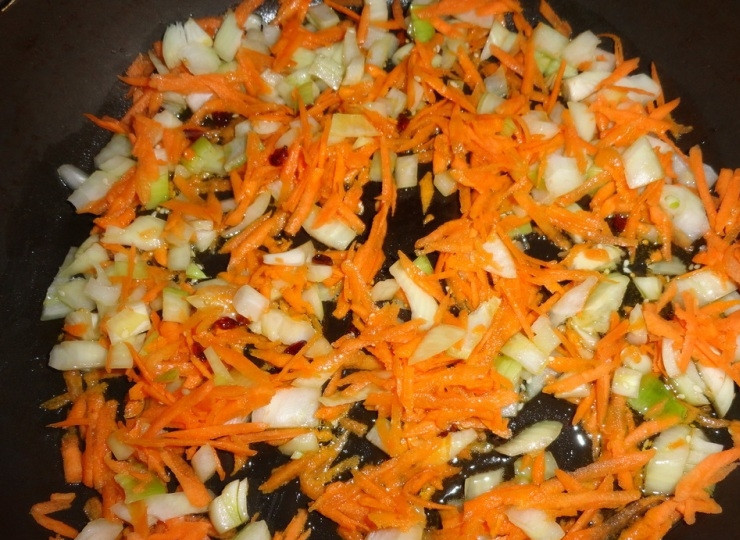 1. Этап. Плов с черносливом: В казан, сотейник или сковороду с высокими краями наливаем оливковое масло и нагреваем его. Теперь высыпаем на раскаленное масло все специи кроме зелени и обжариваем около минуты. Выкладываем нарезанные лук и морковь и жарим примерно три минуты, помешивая, на среднем огне.