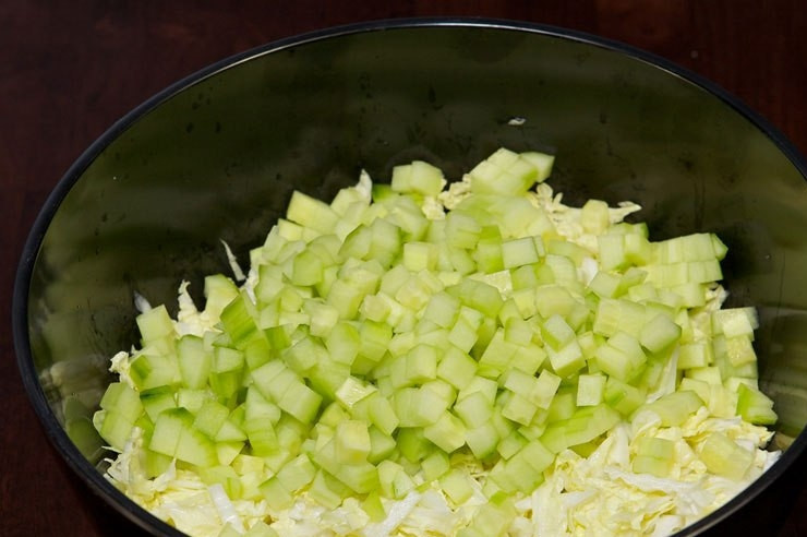 1. Этап. Салат с кукурузой и крабовыми палочками: Огурец нарежьте небольшими кубиками. Добавьте их в салатницу.