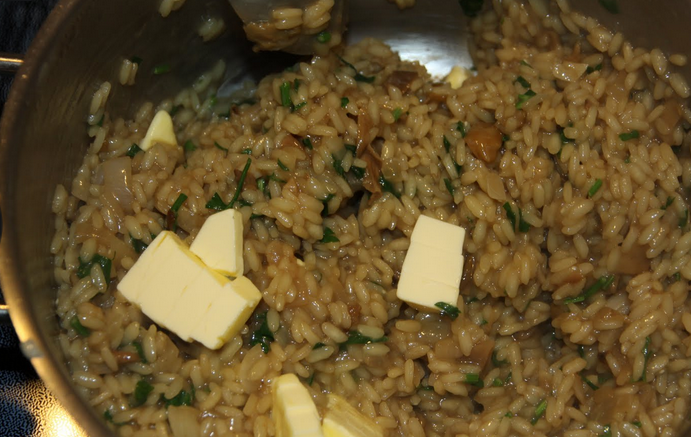 1. Этап. Ризотто с сушеными белыми грибами: Когда рис почти готов, добавляем кусочки сливочного масла, тщательно все перемешиваем. Кладем измельченную петрушку и тертый сыр.