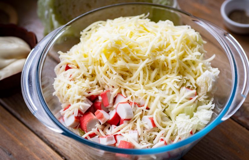 1. Этап. Салат с пекинской капустой, крабовыми палочками и сыром: В просторную миску выложите пекинскую капусту, сыр, крабовые палочки и грецкие орехи.