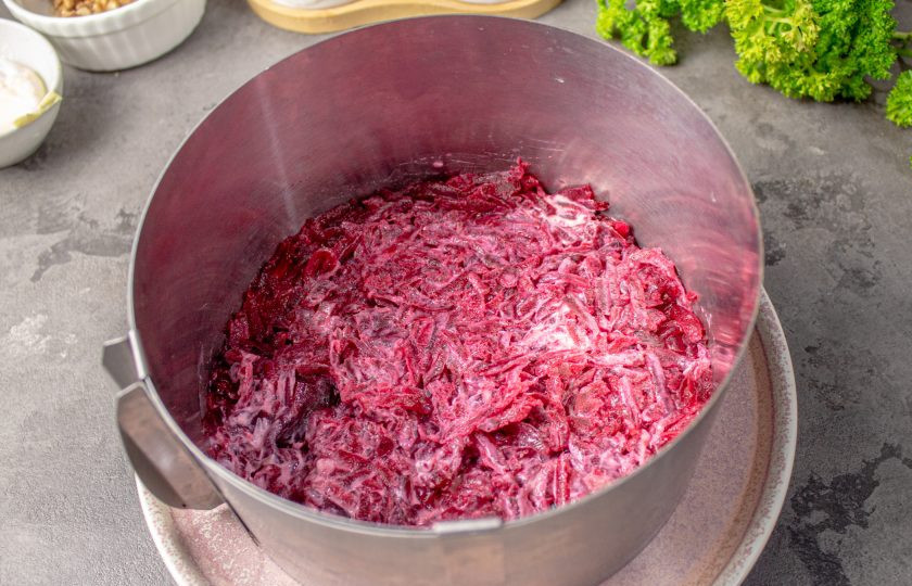 1. Этап. Слоеный салат с курицей, свеклой, морковью и сыром: Установите на блюдо сервировочное кольцо диаметром 14-16 см. Первым слоем выложите половину от общей нормы свеклы, разровняйте и слегка утрамбуйте.
