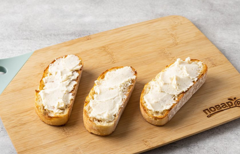 1. Этап. Брускетта с печеным перцем и сыром: Намажьте хлеб творожным сыром.