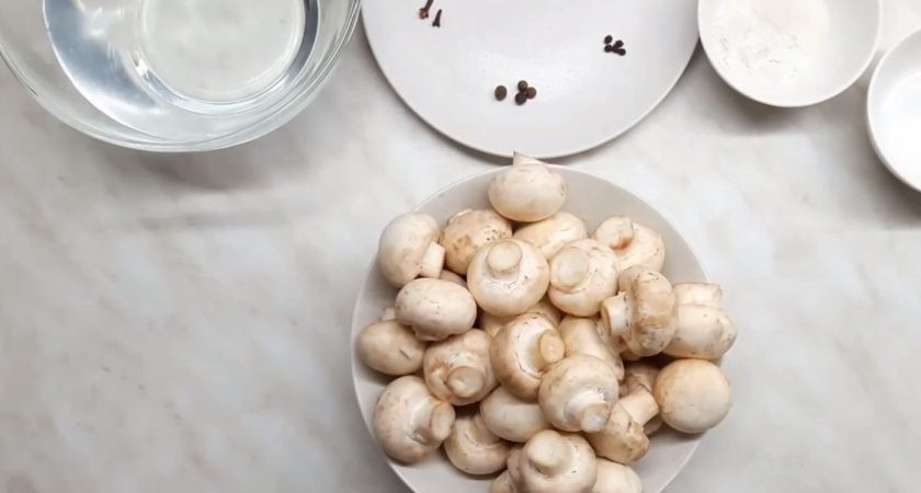 1. Этап. Рецепт маринованных шампиньонов: 1. Для начала разрежьте грибы, если они у вас слишком большие. Затем приготовьте маринад: в воду добавьте острый перец, душистый перец, гвоздику, кориандр, лавровый лист, соль и сахар. Хорошо все перемешайте.