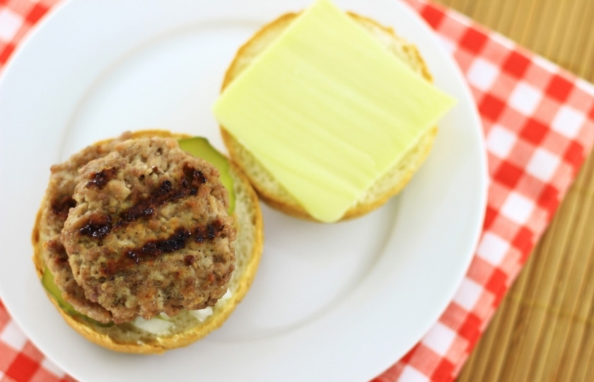 1. Этап. Двойной гамбургер: Теперь на огурцы положите первую котлету из говяжьего фарша.