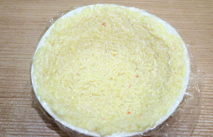 1. Этап. Рисовый салат на Новый год Свиньи: В рис добавьте немного майонеза и перемешайте. Распределите по тарелке.