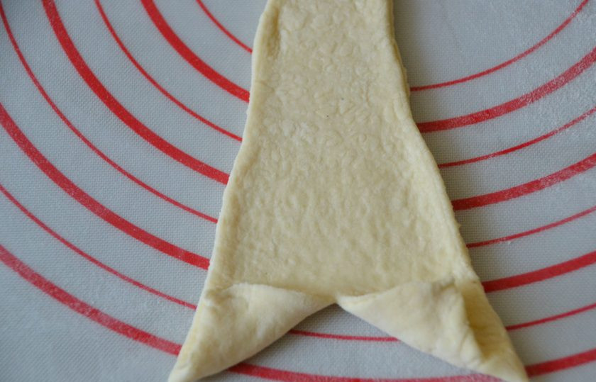 1. Этап. Круассаны с заварным кремом: Подверните уголки теста и начинайте сворачивать от основания треугольника к его вершине.