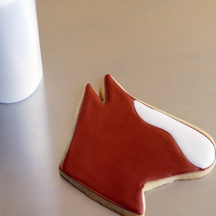 1. Этап. Печенье Лошадь: 2. Контуры нужны для того, чтобы легче было заполнить голову коня глазурью другого цвета. Например, для белого цвета используйте сахарную пудру, разведенную с лимонным соком. Заполните белым мордочку. В качестве коричневого используйте растопленный со сливками или сливочным маслом шоколад. Можно использовать и готовые кондитерские краски.