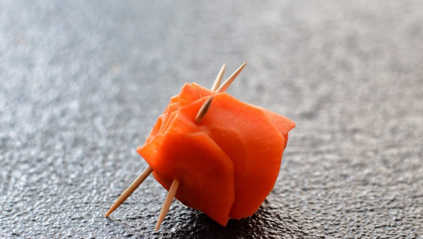 1. Этап. Розы из моркови: Скрутите морковный ряд в рулон, начиная от самого первого кружочка. Затем скрепите рулончик зубочистками.