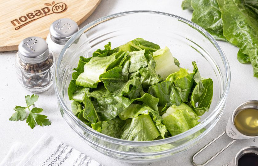 1. Этап. Салат с перцем, огурцом и сыром: Салатные листья помойте, обсушите и нарежьте на кусочки среднего размера. Либо порвите их руками. Выложите в глубокую миску.