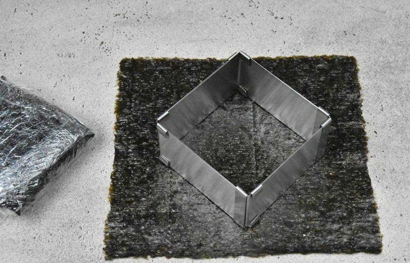 1. Этап. Суши сэндвич с креветкой: Выложите на рабочую поверхность лист нори, блестящей стороной вниз. Очень удобно собирать начинку используя сервировочную квадратную форму.