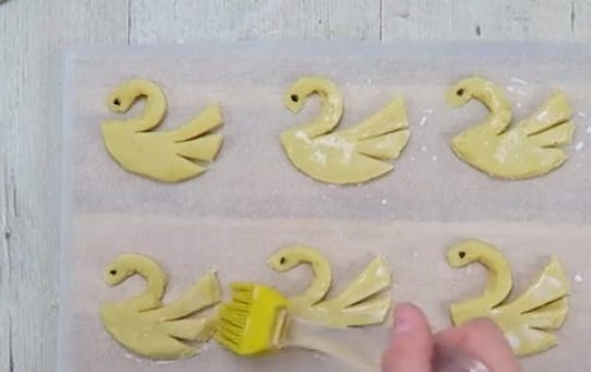 1. Этап. Песочное печенье Лебеди: 8. Выложите печенье на противень, покрытый пергаментом, смажьте молоком и посыпьте фигурки коричневым сахаром.